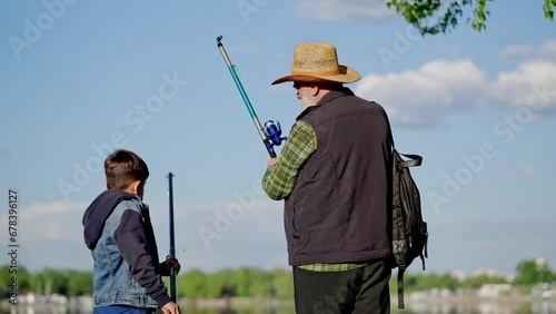 Rear view pensioner roll spinning. Fisherman with his grandson bringing fishing rod and come back home. Grandfather angler showing grandchild how to fold telescopic fishrod outdoors photo