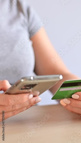 A woman makes an online purchase on a smartphone using a credit card. Vertical video.  photo