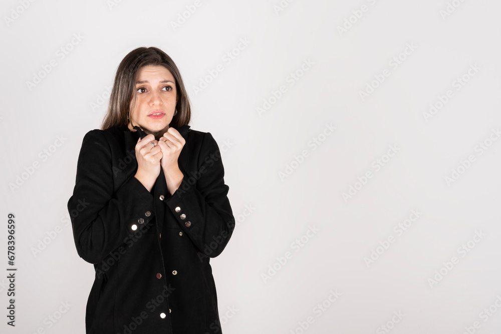 Studio portrait of young blonde woman wearing a black coat with expression of cold and disgust Studio portrait of young blonde woman wearing a black coat with expression of cold and disgust