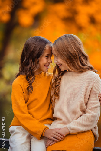 beautiful girls twin sisters on a walk in the park. children teenagers having fun in autumn