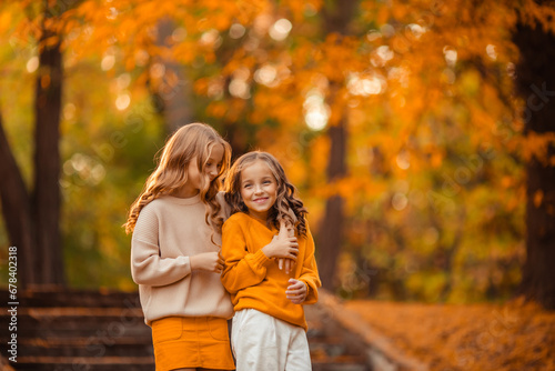 beautiful girls twin sisters on a walk in the park. children teenagers having fun in autumn