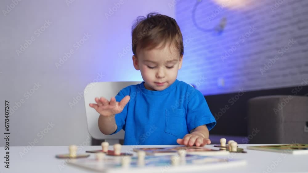 Charming little toddler in blue shirt playing games at desk. Calm baby boy stands up and walks away. Charming little toddler in blue shirt playing games at desk. Calm baby boy stands up and walks away.