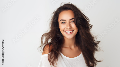  Portrait of a young and beautiful brunette woman on white background, smiles and laughs to the camera. Advertising concept.