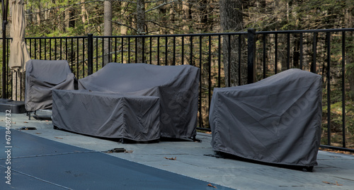 outdoor furniture covered for the season (end of year, winter) along with pool with cover (safety) chairs, sofa, couch, swimming pool, patio, back yard, stone, granite, protetive rain cover, sheath