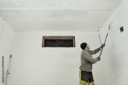 Skilled Craftsman Painting a Room in Fresh Overalls with Precision and Care.