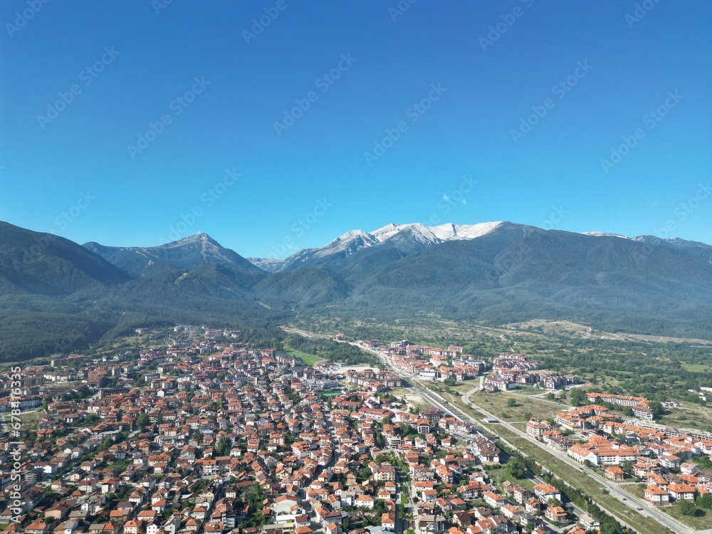 Aerial shot of the red roofs of houses in Bansko surrounded by a mountain range, Bulgaria