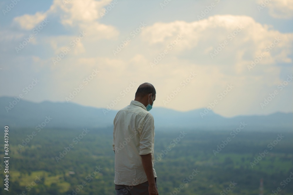 Man wearing a mask overlooking the mountains in Pidurangala Rock (Sigiriya)