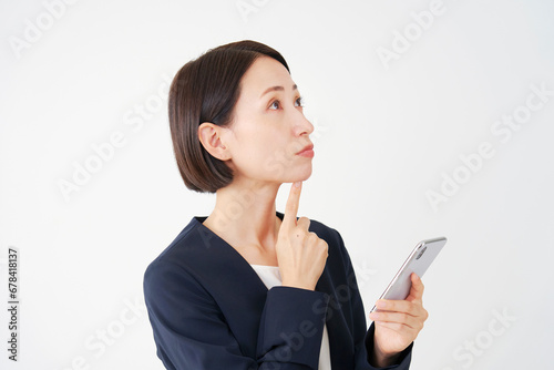 スマートフォンを持って考える中年のビジネスウーマン　白背景 © siro46