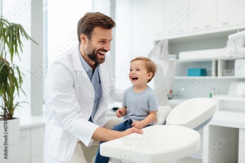 Cheerful pediatrician smiling while examining little boy patient in clinic