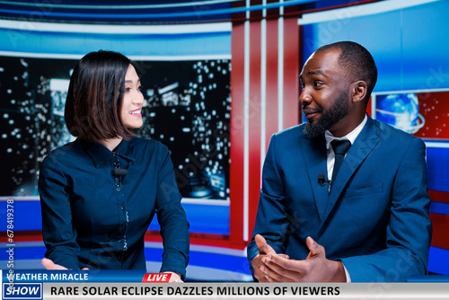 Presenters talk about rare solar eclipse appearing on sky, diverse newscasters presenting weather miracle and beautiful light over sun. Team of journalists on night show discussing natural event. photo