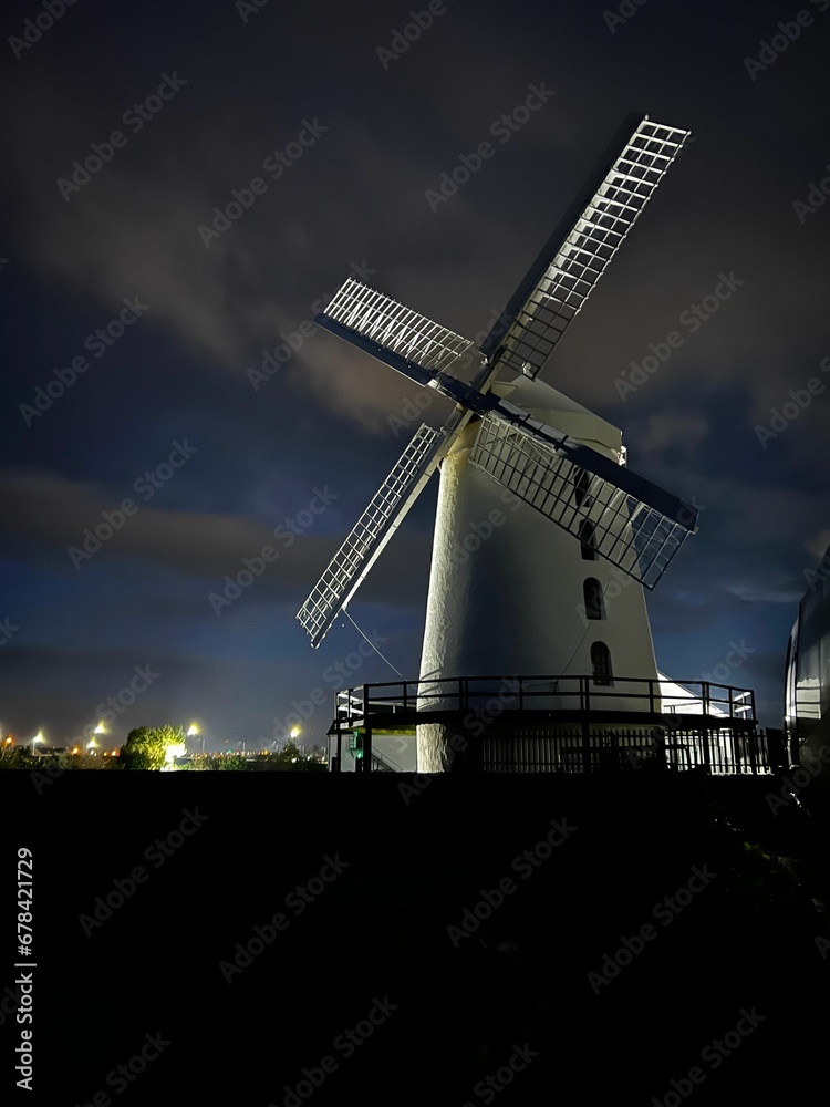 Vertical shot of an old windmill against a cloudy night sky
