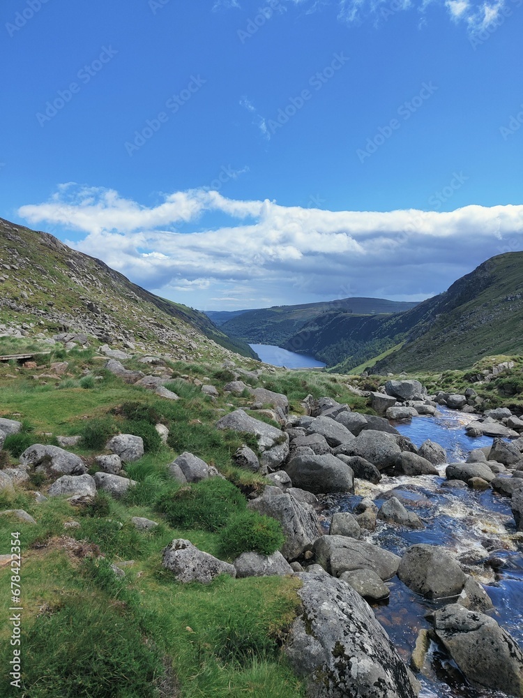 Vertical shot of stones, mountains and a river in distance in Glendalough National Park Vertical shot of stones, mountains and a river in distance in Glendalough National Park