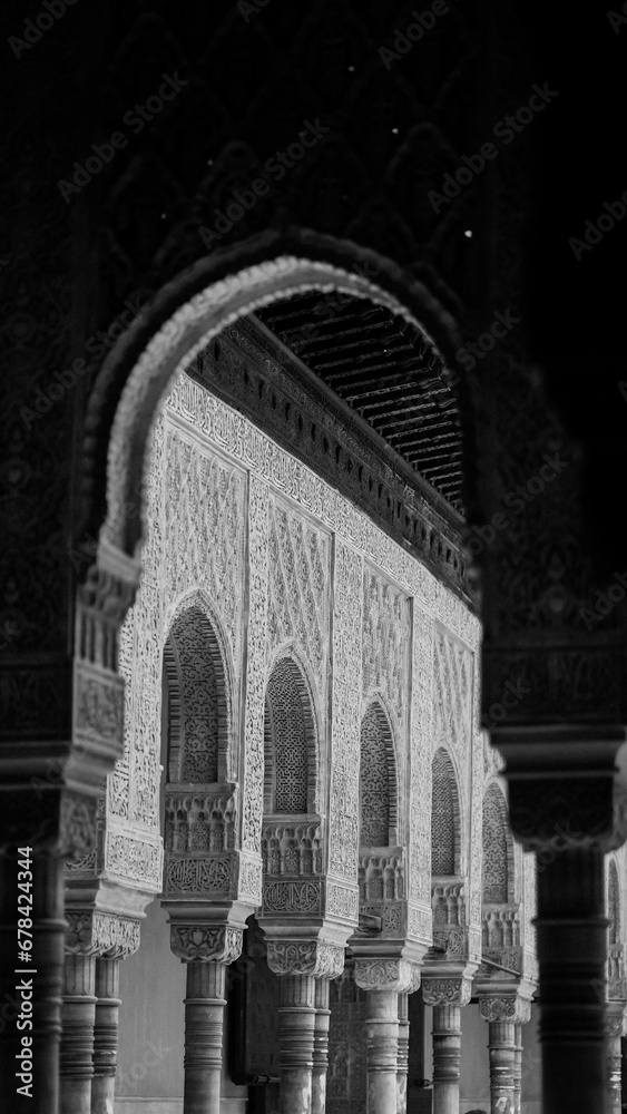 Vertical grayscale shot of Islamic architecture with quranic inscriptions on Alhambra Castle