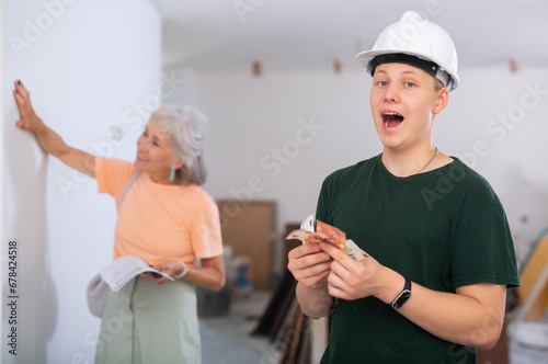 Obraz na plátně Portrait of happy teenage boy holding bunch of cash he earned for first part-time job in construction site