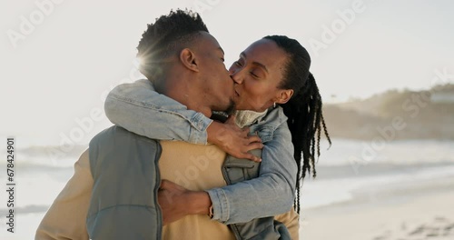 Kiss, happy and black couple at the beach with hug for love, date and bonding on holiday. Laughing, nature and an African man and woman with care and affection at the sea for a vacation or honeymoon photo