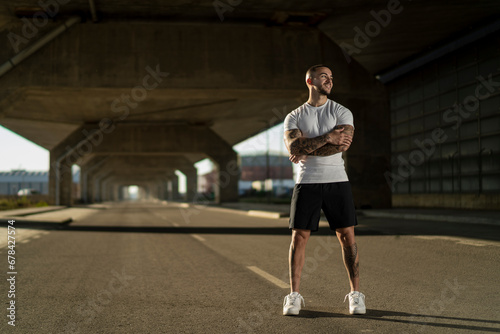 Obraz na płótnie Chico joven musculoso y tatuado haciendo ejercicio y usando smartphone en carretera w salonie