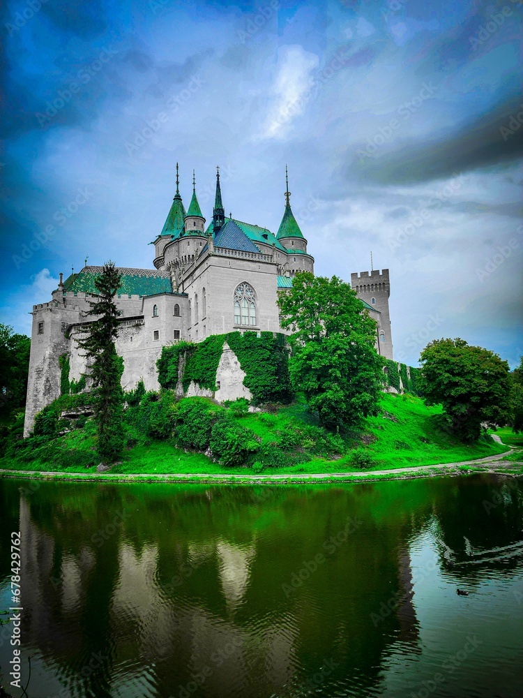 Vertical shot of the Bojnice Castle reflected on waters under cloudy sky Vertical shot of the Bojnice Castle reflected on waters under cloudy sky