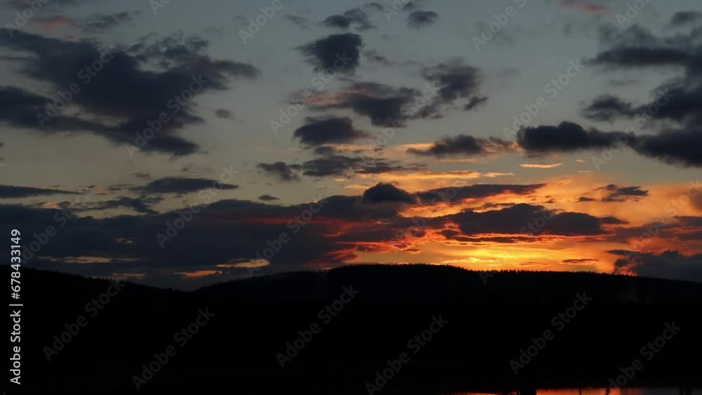 Time lapse of sunset view on cloudy sky with silhouette of forested hills Time lapse of sunset view on cloudy sky with silhouette of forested hills