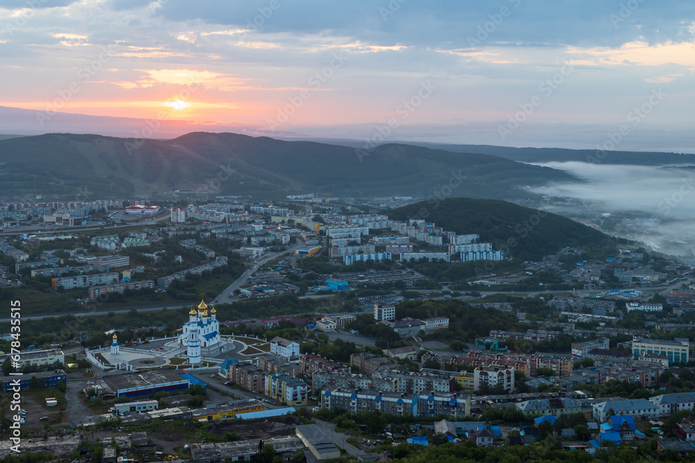 Morning cityscape. Top view of the cathedral, buildings and streets. Residential urban areas at sunrise. Fog over the ground. City of Petropavlovsk-Kamchatsky, Kamchatka Krai, Far East of Russia.