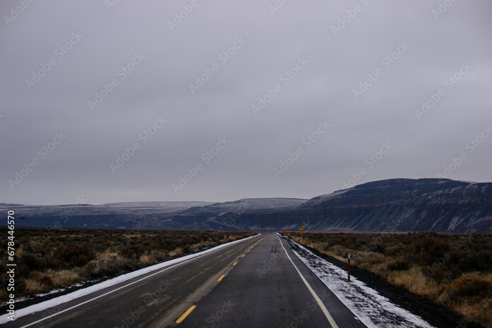 Asphalt road in the middle of high mountains, covered with fog and clouds, at dusk. American winter landscape of a mountainous area covered with fir forest Asphalt road in the middle of high mountains, covered with fog and clouds, at dusk. American winter landscape of a mountainous area covered with fir forest