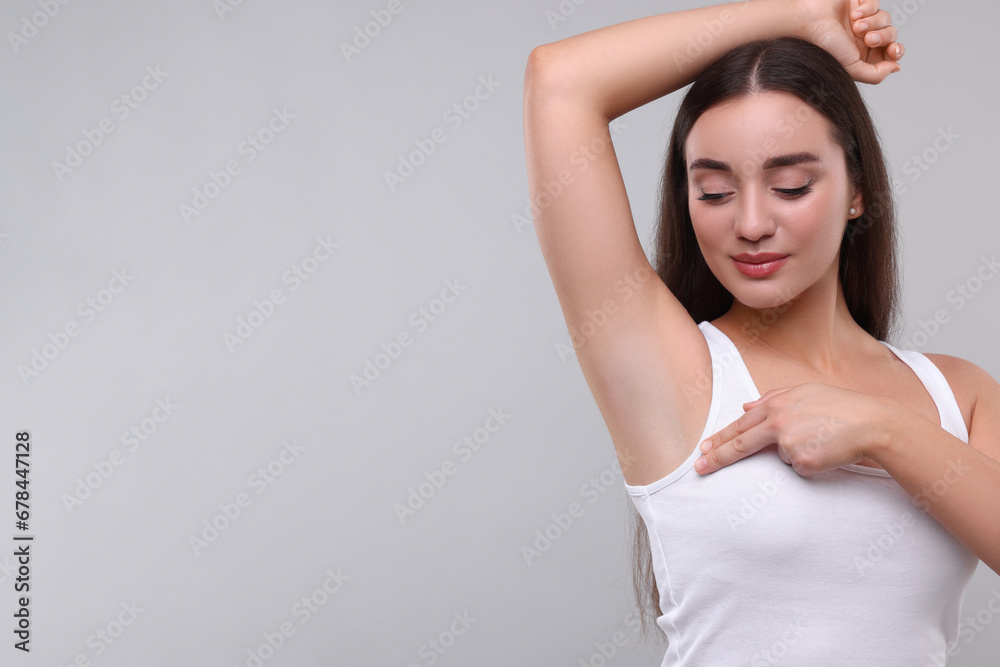 Beautiful young woman doing breast self-examination on light grey background, space for text Beautiful young woman doing breast self-examination on light grey background, space for text