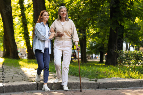 Obraz na płótnie Senior lady with walking cane and young woman in park
