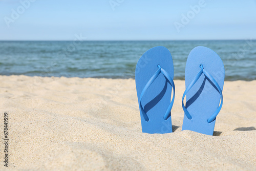 Stylish blue flip flops on beach sand, space for text