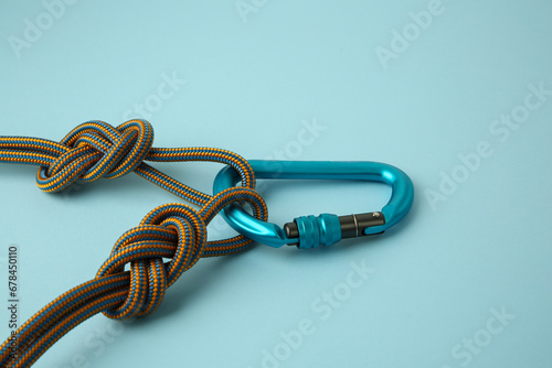 One metal carabiner with ropes on light blue background, closeup