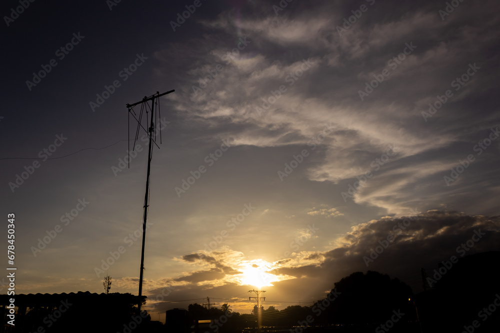silhouette of electricity post on the sunset sky and cloud background