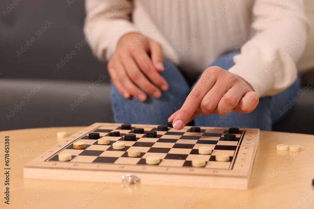 Woman playing checkers at wooden table, closeup Woman playing checkers at wooden table, closeup