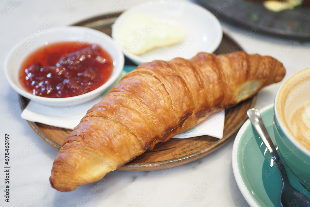 fresh baked croissant served with butter and jelly on table 