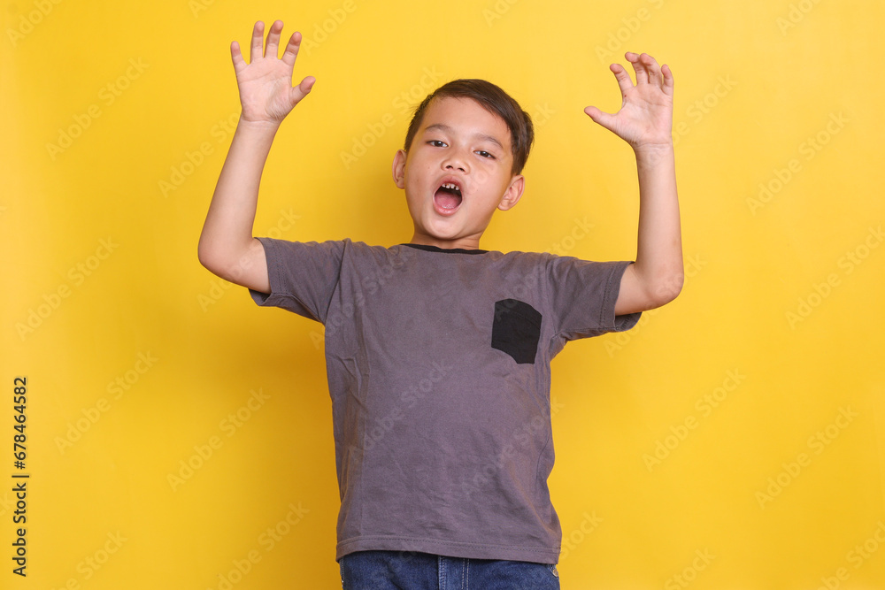 Funny Asian little boy roaring isolated on a yellow background Funny Asian little boy roaring isolated on a yellow background