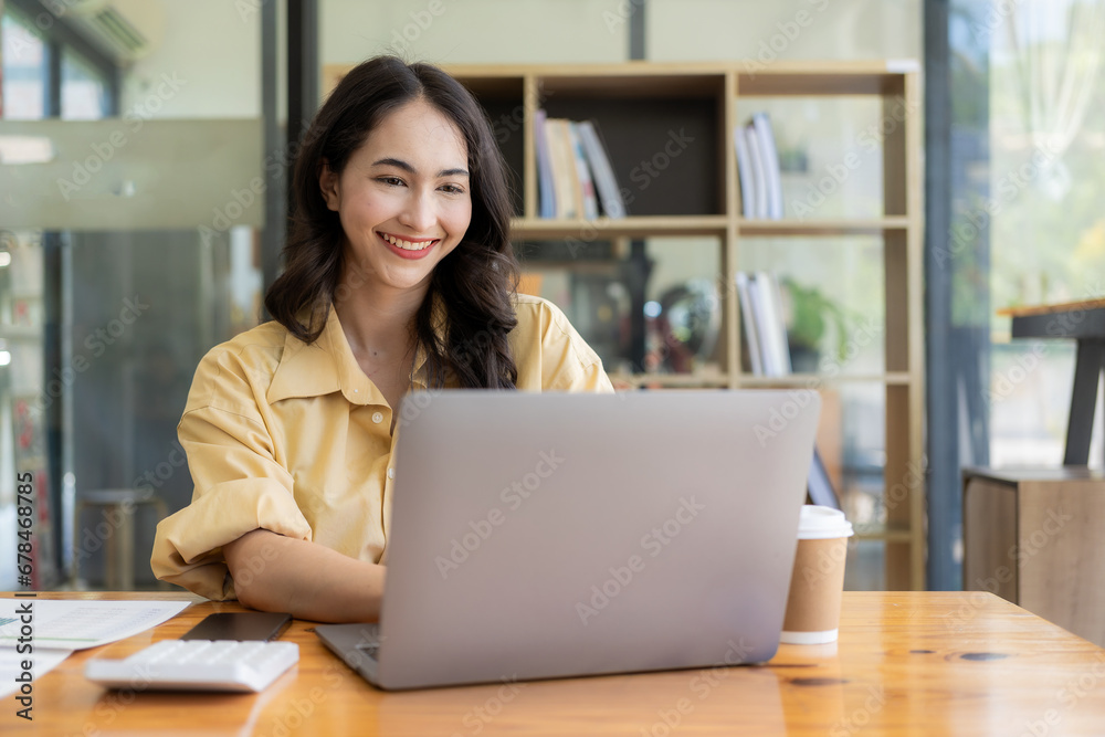 Ambitious Asian girl working from home Looking at laptop screen and financial documents, woman is checking email or doing research while working remotely. Ambitious Asian girl working from home Looking at laptop screen and financial documents, woman is checking email or doing research while working remotely.
