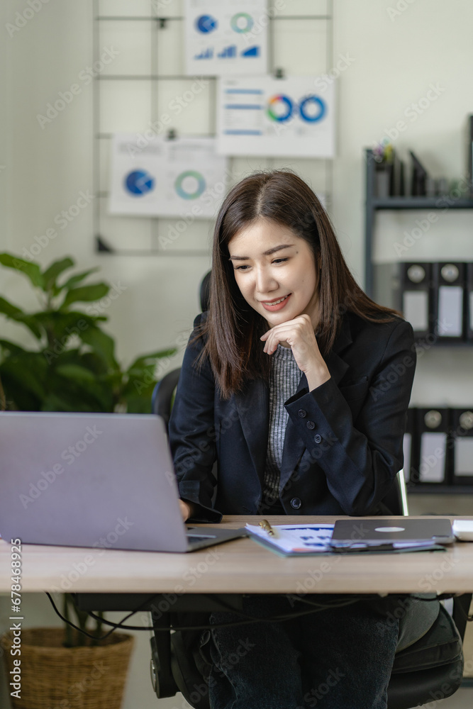 Ambitious Asian girl working from home Looking at laptop screen and financial documents, woman is checking email or doing research while working remotely. Ambitious Asian girl working from home Looking at laptop screen and financial documents, woman is checking email or doing research while working remotely.