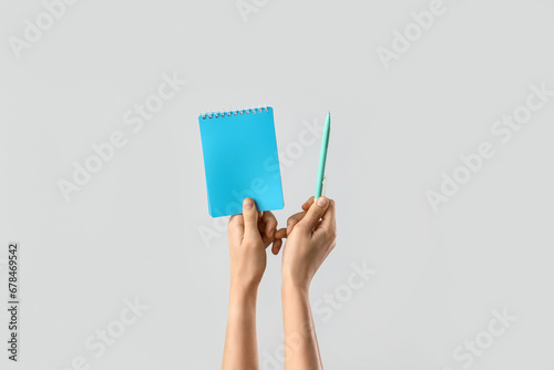 Hands with notebook and pen on light background