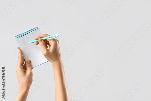 Hands with notebook and pen on light background