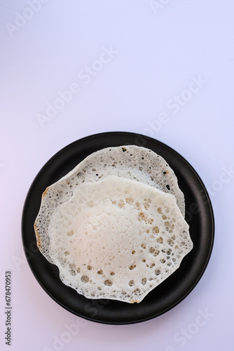 Appam, Kerala breakfast food duck curry or hot and spicy chickpea Masala and milk tea chai, Christian breakfast on dark black background. fermented rice pan cake. Top view of Indian veg food.