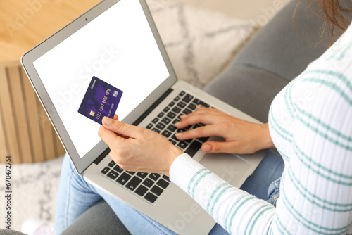 Young woman with credit card using laptop at home, closeup
