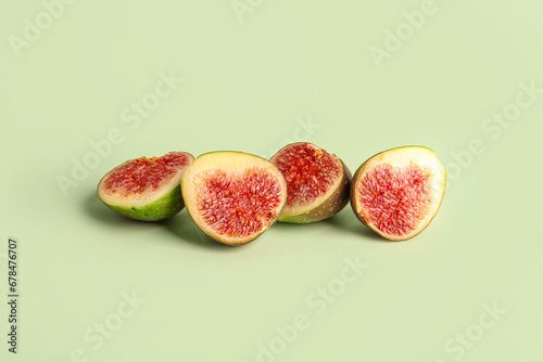 Halves of fresh ripe figs on green background