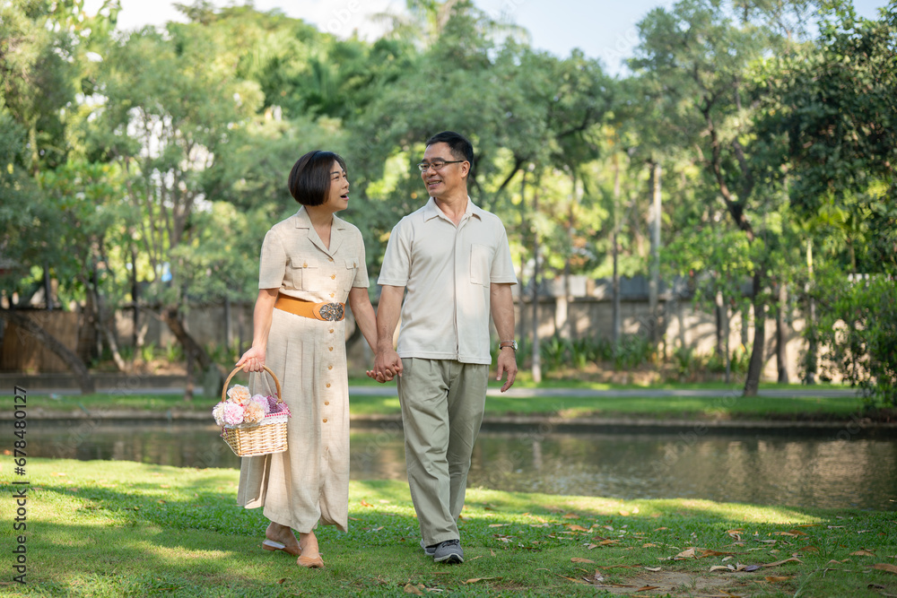 Fototapeta premium Happy Asian senior couples are enjoying talking and holding hands while strolling around the park.