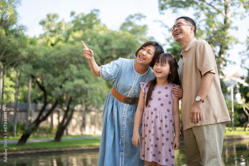 Kind Asian grandparents are having fun with their granddaughter, strolling around the park together. Kind Asian grandparents are having fun with their granddaughter, strolling around the park together.