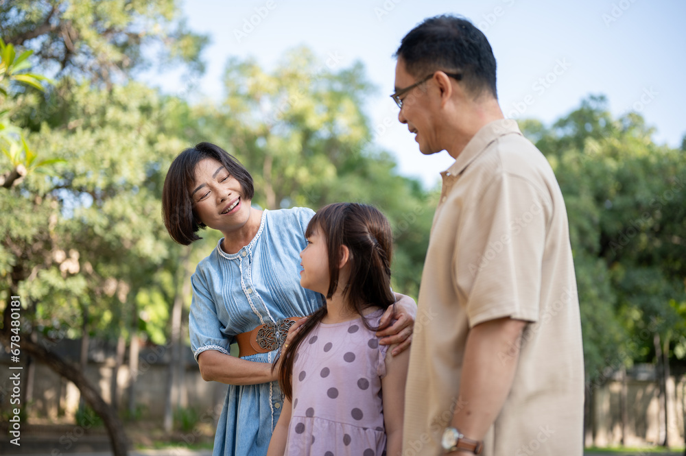 Kind Asian grandparents are having fun with their granddaughter, strolling around the park together. Kind Asian grandparents are having fun with their granddaughter, strolling around the park together.