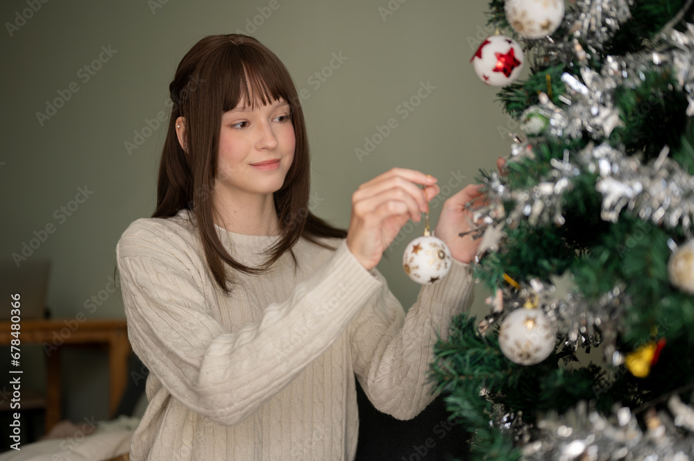 A beautiful woman is enjoying decorating a Christmas tree with beautiful ornaments. A beautiful woman is enjoying decorating a Christmas tree with beautiful ornaments.