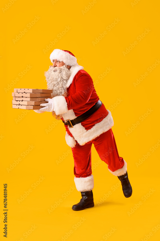 Santa Claus with pizza boxes on yellow background Santa Claus with pizza boxes on yellow background