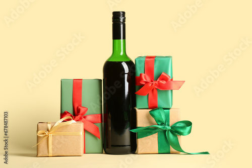 Bottle of wine and Christmas gift boxes on yellow background