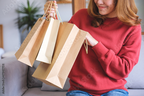 Closeup image of a young woman holding and opening shopping bags at home
