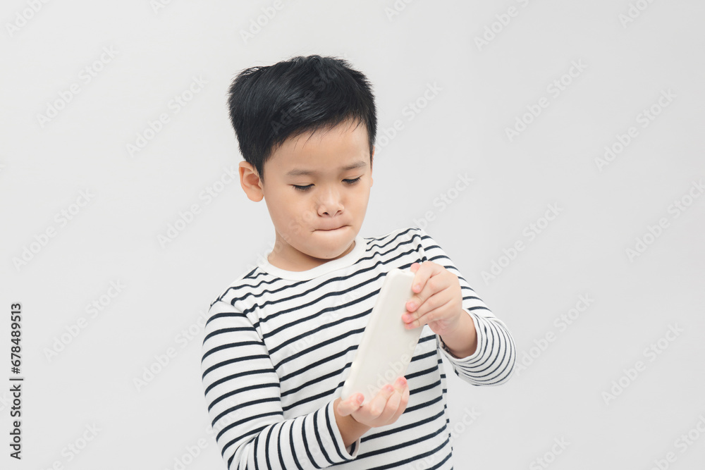 Serious little boy using smartphone over white banner background. Serious little boy using smartphone over white banner background.