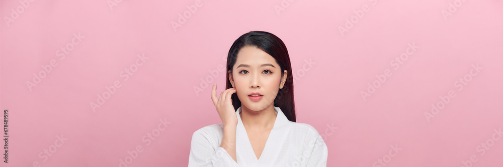 Smiling beautiful Asian woman touching her face on isolated studio pink background. Panorama Smiling beautiful Asian woman touching her face on isolated studio pink background. Panorama