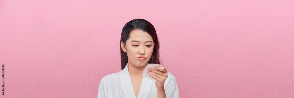 Woman removing oil from face using blotting papers Woman removing oil from face using blotting papers