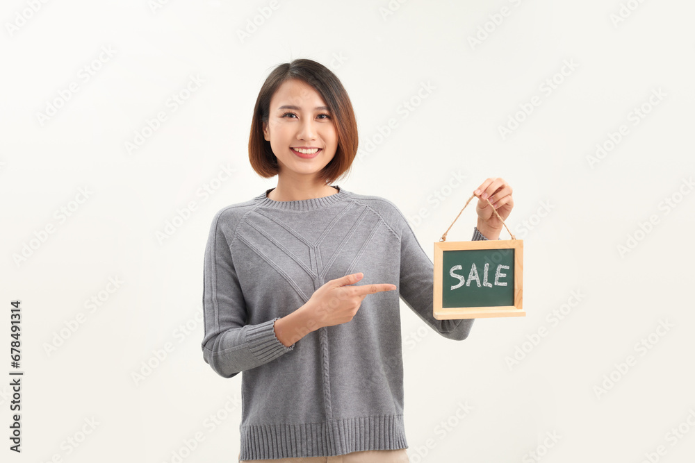Young woman shop owner, wearing apron holding SALE word banner Young woman shop owner, wearing apron holding SALE word banner